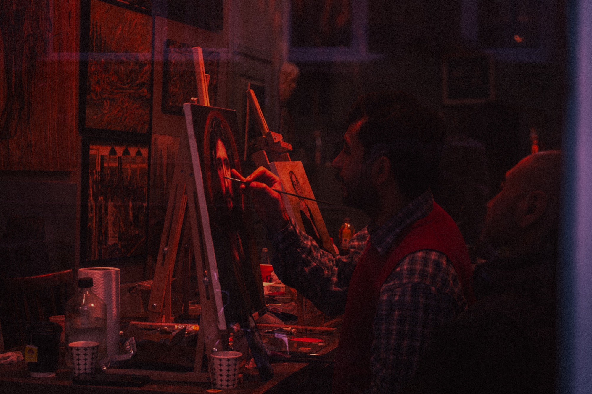 Painter at easel through window, red ambient light